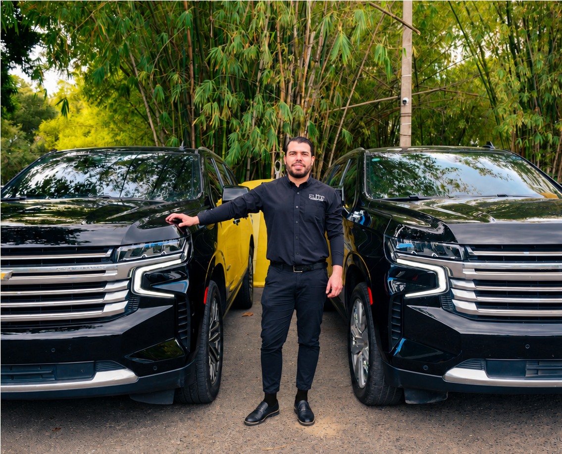 Elite Transport driver Carlos wearing black socks between two black SUVs